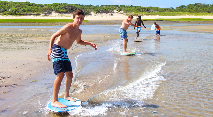 Boys skimboarding on the beach